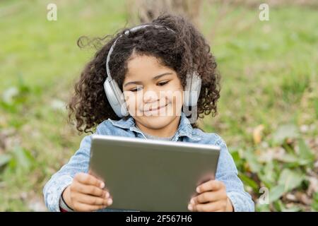 Boy using digital tablet while listening music in nature Stock Photo