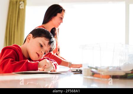 Boy studying while mother working at home Stock Photo