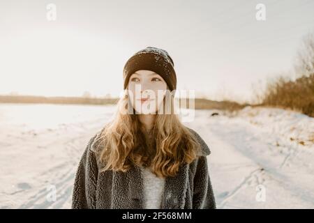 Portrait of beautiful teenage girl standing outdoors and smiling against rising winter sun Stock Photo