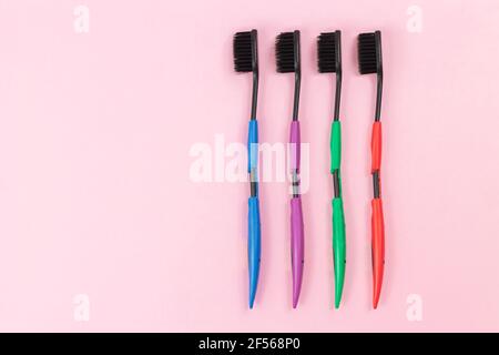 Set of colorful plastic toothbrushes with black bristles on pink background top view. Space for text Stock Photo