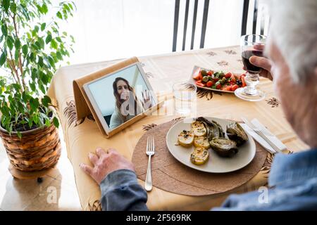 Senior man on video call with daughter while having food at table Stock Photo
