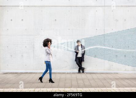 Graphic visualization of data exchanged by man and woman using smart phones outdoors Stock Photo