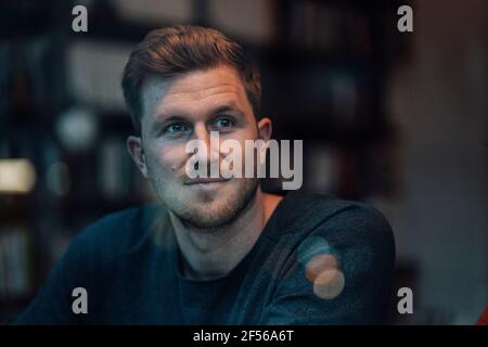 Mid adult man looking away while sitting at cafe Stock Photo