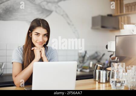 Female barista cafe owner using a laptop computer waiting for new clients. Stock Photo