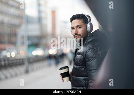 Handsome man with headphones holding coffee cup Stock Photo