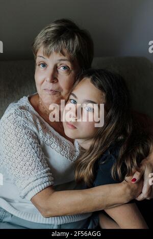 Grandmother with arm around embracing granddaughter Stock Photo