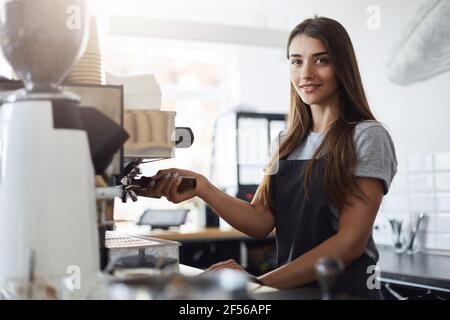 Female cafe owner preparing coffee using a portafilter and a coffee machine Stock Photo