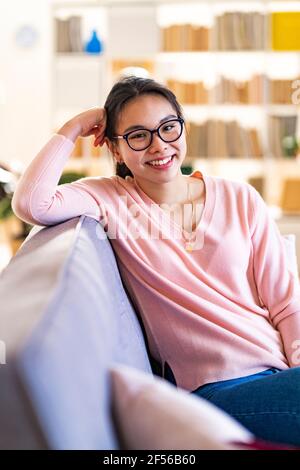 Smiling woman sitting on sofa at home Stock Photo
