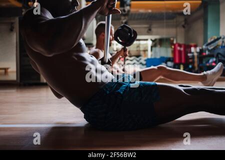 Sports people doing strength training while exercising with barbell in gym Stock Photo