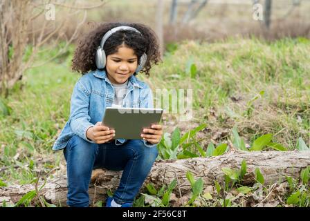 Boy wearing headphones using digital tablet in nature Stock Photo