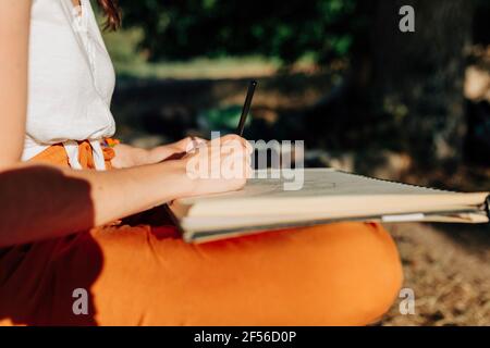 Young woman artist drawing in spiral notebook Stock Photo