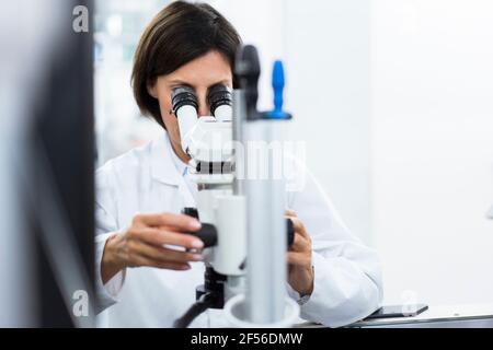 Female scientist using microscope at laboratory Stock Photo