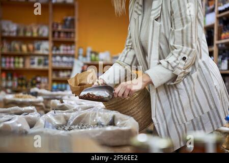 Woman with serving scoop pouring organic food in paper bag Stock Photo