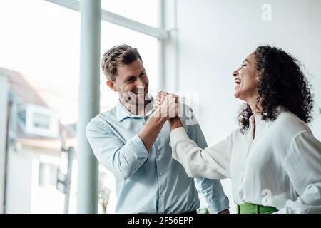 Smiling business people standing with hands clasped at cafe Stock Photo