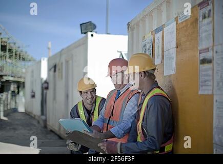 Smiling male construction workers discussing at construction site Stock Photo