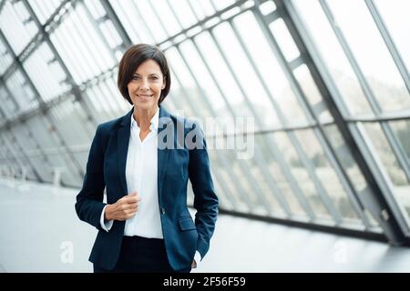 Confident female professional standing in corridor Stock Photo