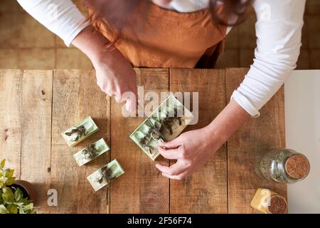 Woman cutting pieces of organic handmade soap on cutting board at workshop Stock Photo