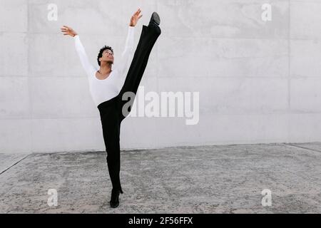 Flexible male dancer looking up while stretching leg against wall Stock Photo