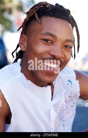 Young black man with dreadlocks laughing while holding his head ...