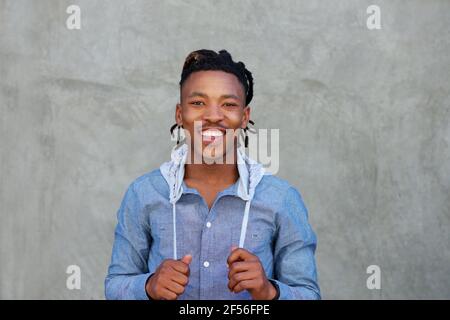 Portrait of smiling black man with dreadlocks standing against wall Stock Photo