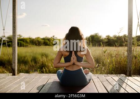 Woman with hands clasped behind back practicing yoga at gazebo Stock Photo