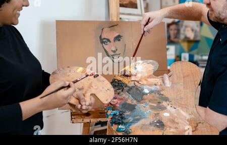 Male artist teaching painting to female painter Stock Photo