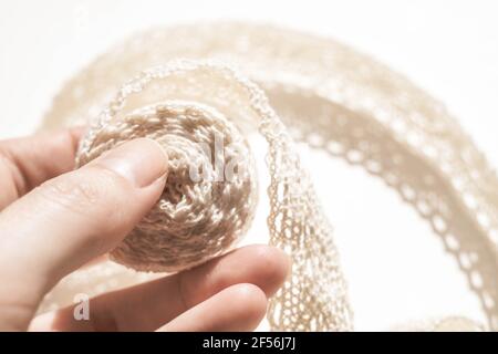 Pale beige lace in female fingers on a white table Stock Photo