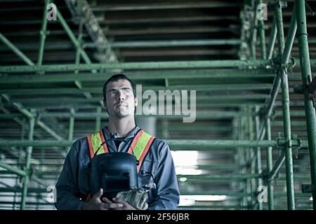 Thoughtful male construction worker looking away at construction site Stock Photo