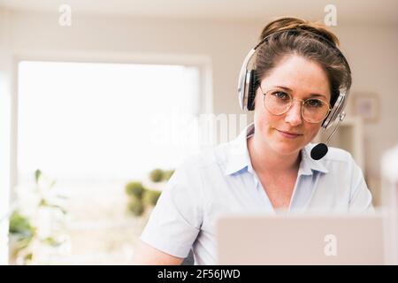 Businesswoman in eyeglasses wearing wireless headphones Stock Photo