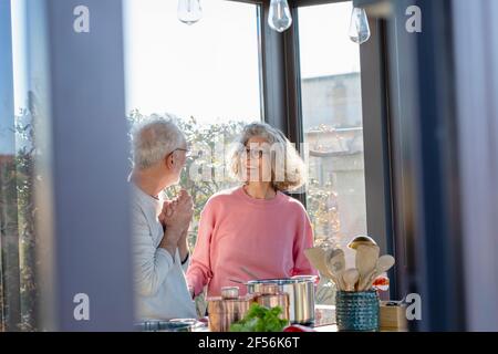 Senior couple looking at each other while standing at home Stock Photo