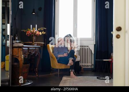 Smiling senior couple using mobile phone while sitting at home Stock Photo
