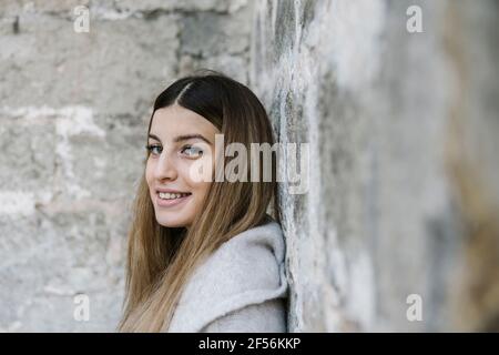 Smiling woman leaning on wall Stock Photo