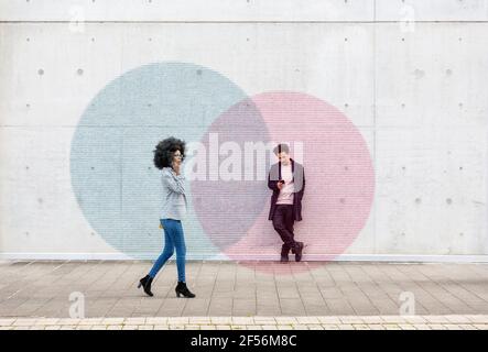 Graphic visualization of data exchanged by man and woman using smart phones outdoors Stock Photo
