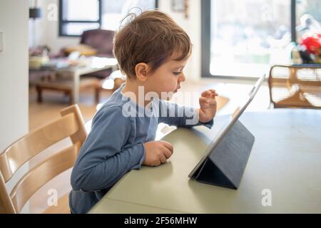 Boy using digital tablet during online class at home Stock Photo