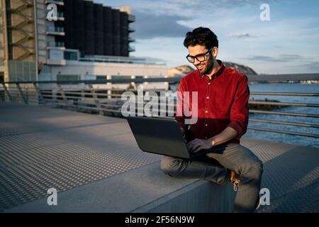 Smiling male freelance worker using laptop on bench Stock Photo