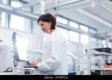 Female technician working on computer at factory Stock Photo