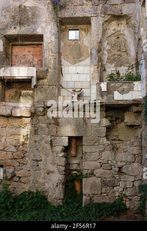 Dilapidated stone house, with exposed toilet Stock Photo