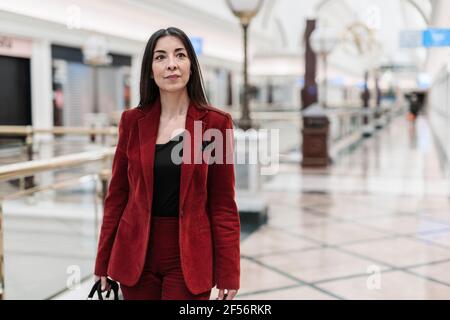 Confident mature businesswoman in red blazer walking at subway station Stock Photo