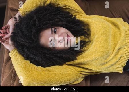 Curly haired woman lying on sofa at home Stock Photo