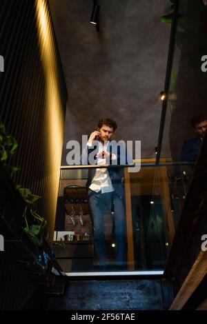 Businessman checking time while talking on smart phone at cafe Stock Photo