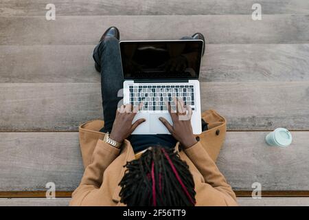 Man using laptop while sitting on steps Stock Photo