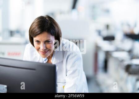 Smiling female engineer using computer at factory Stock Photo