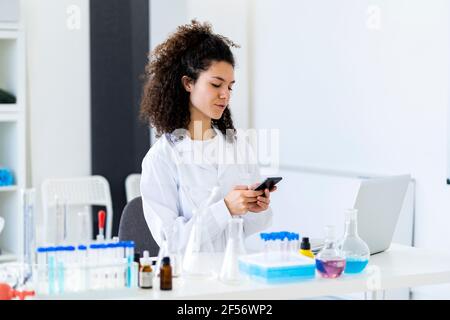 Young female researcher using smart phone at clinic Stock Photo