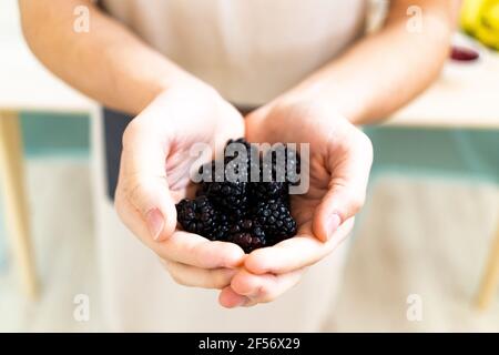 Man holding fresh blackberries in kitchen Stock Photo
