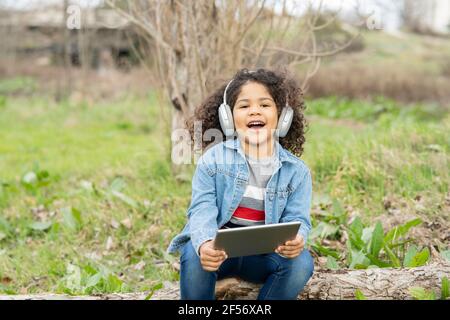 Cute boy wearing headphones while using digital tablet in nature Stock Photo