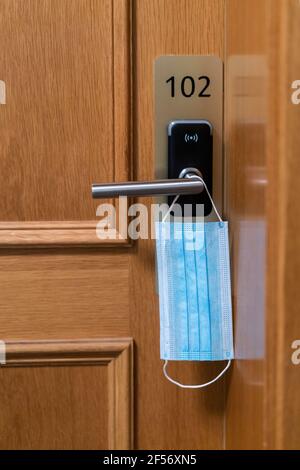 Protective face mask hanging on laptop in office Stock Photo - Alamy