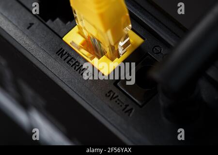 Wireless modem router with yellow cable and LAN port for connection on a black background. wireless LAN technology with devices based on IEEE 802.11 s Stock Photo