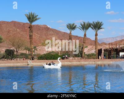 Timna Valley, Israel -  February 20, 2021: People ride boat in the form of swan on an artificial lake in the Timna Valley. The Arava Desert in Israel. Stock Photo