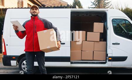 Young man delivering package. Using tablet to read the order. High quality photo Stock Photo