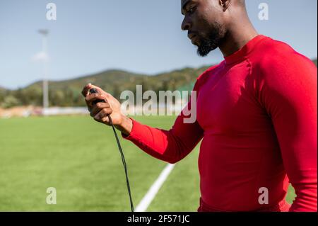 Side view of black sportsman in a football field checking times with a stopwatch. Serious concentrated face. Stock Photo